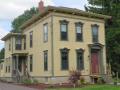 Another three-bay Victorian Era Italianate Style home with the distinctive low pitched roof, ornate decorative brackets under the eaves and tall windows with over-moldings. Recently painted in period-appropriate natural earth tone colors.